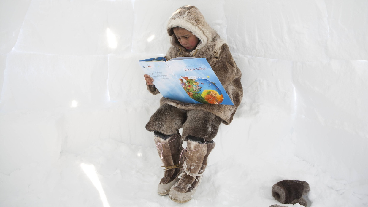 Greta kennt er vermutlich auch schon: Ein junger Inuit in der Arktis liest ein Buch über die Zukunft der sich erwärmenden erde.