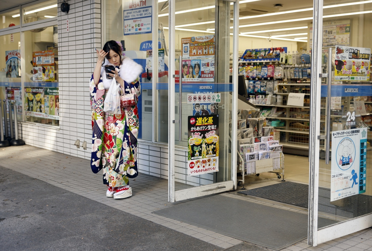 Eine junge Teilnehmerin  wartet nach der Zeremonie vor einem Laden in Yokohama.