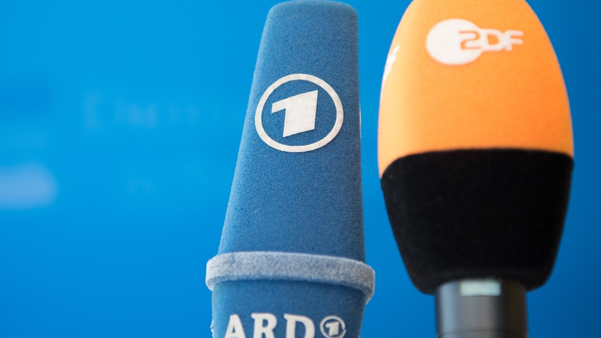 Die Mikrofone von ARD und ZDF stehen vor einer Pressekonferenz nebeneinander.