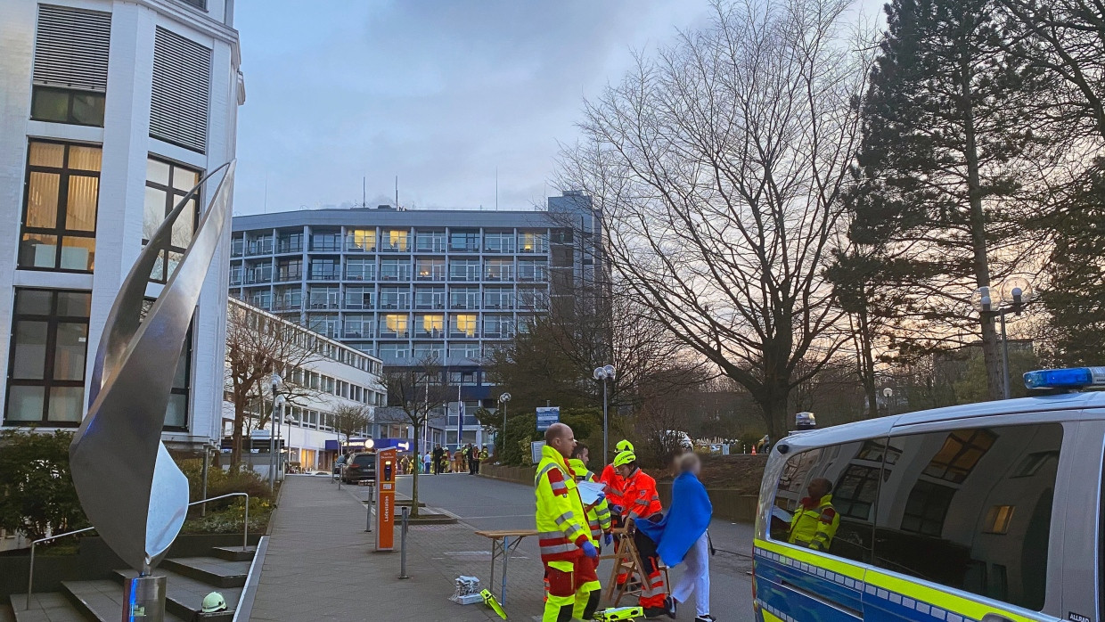 Einsatzkräfte von Polizei und Rettungsdienst stehen vor einem Aachener Krankenhaus.