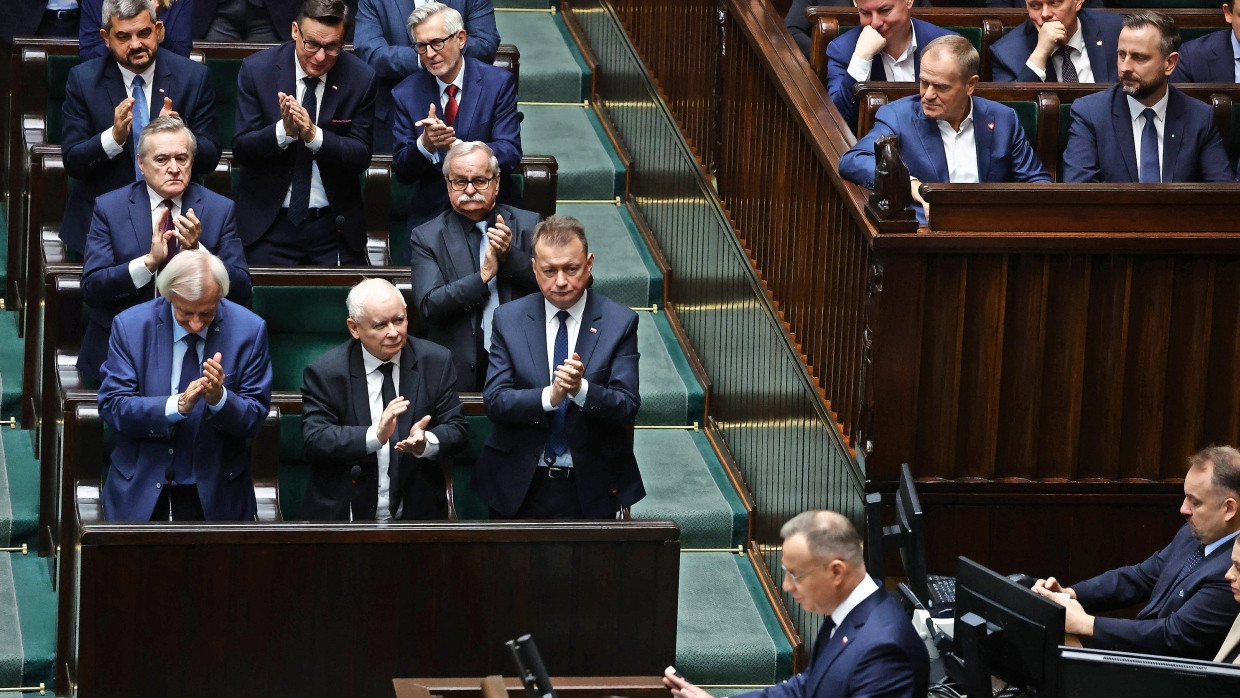 Gespalten: Die PiS-Fraktion im polnischen Parlament applaudiert, Tusks liberale Regierung schaut skeptisch, während Präsident Duda spricht.