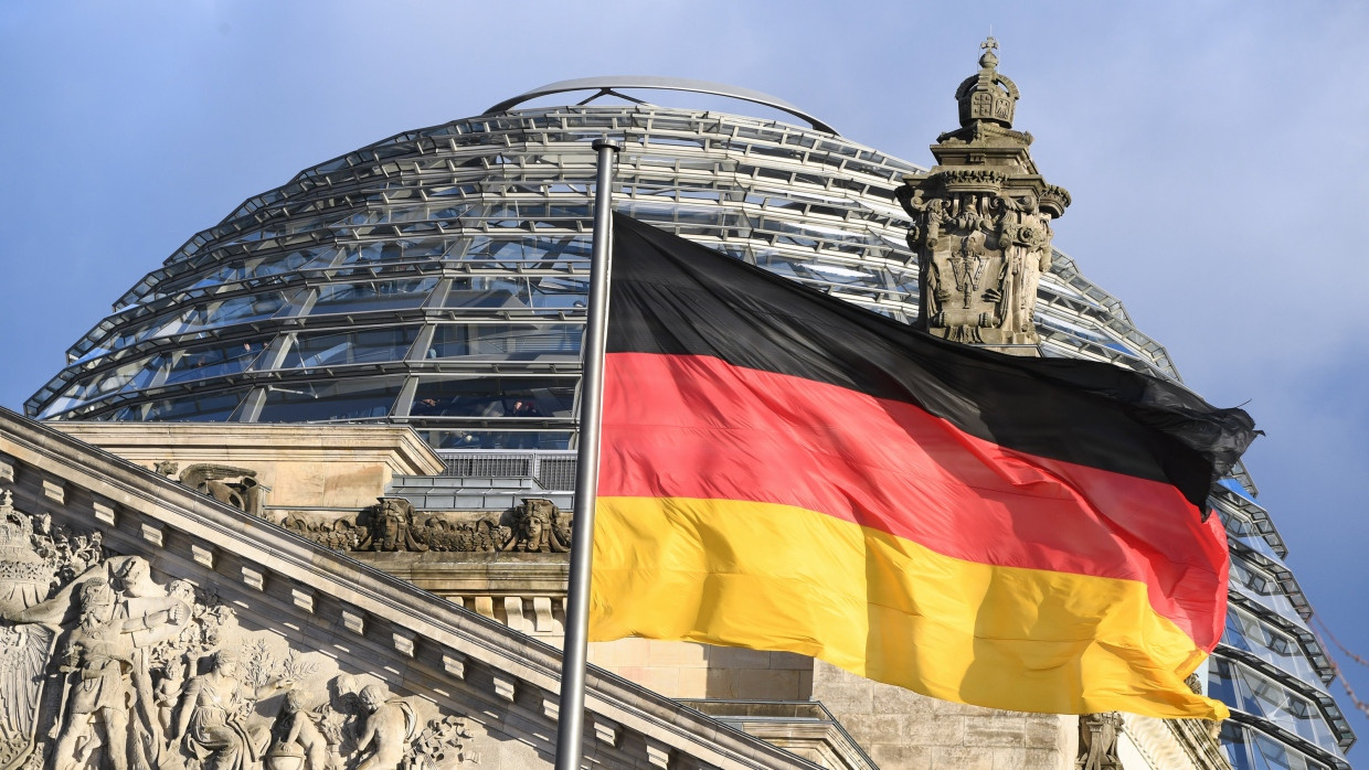 Die schwarz-rot-goldene Flagge weht vor der Kuppel des Reichstages.