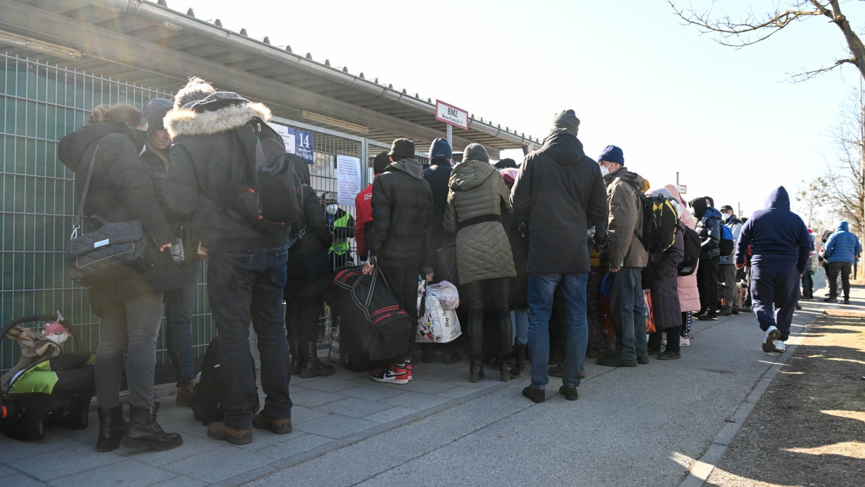 Geflüchtete warten vor einer Flüchtlingsunterkunft in München auf Einlass.