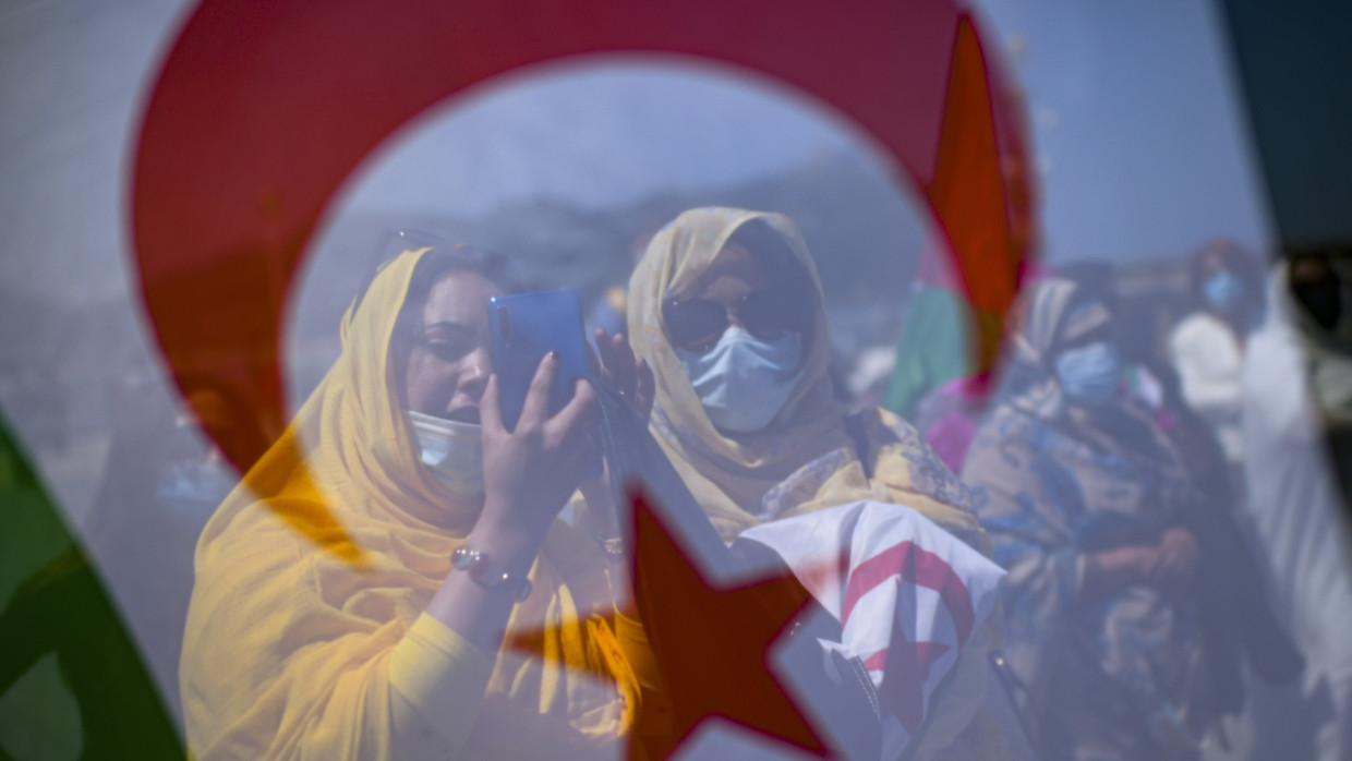 Saharische Demonstrantinnen stehen bei einem Protest im spanischen San Sebastian im Jahr 2021 hinter einer Fahne der Westsahara.