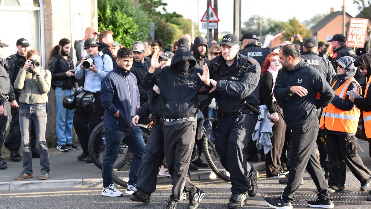 Die Polizei führt einzelne Demonstranten einer rechtsradikalen Gruppe ab, die vor einem Flüchtlingsheim maskiert protestierten.