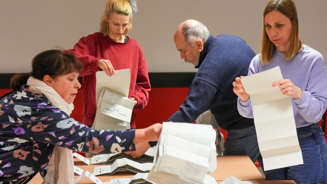 Wahlhelfer sortieren bei der Stimmauszählung im Berliner Carl von Ossietzky-Gymnasium im Wahllokal 317 die Stimmzettel.