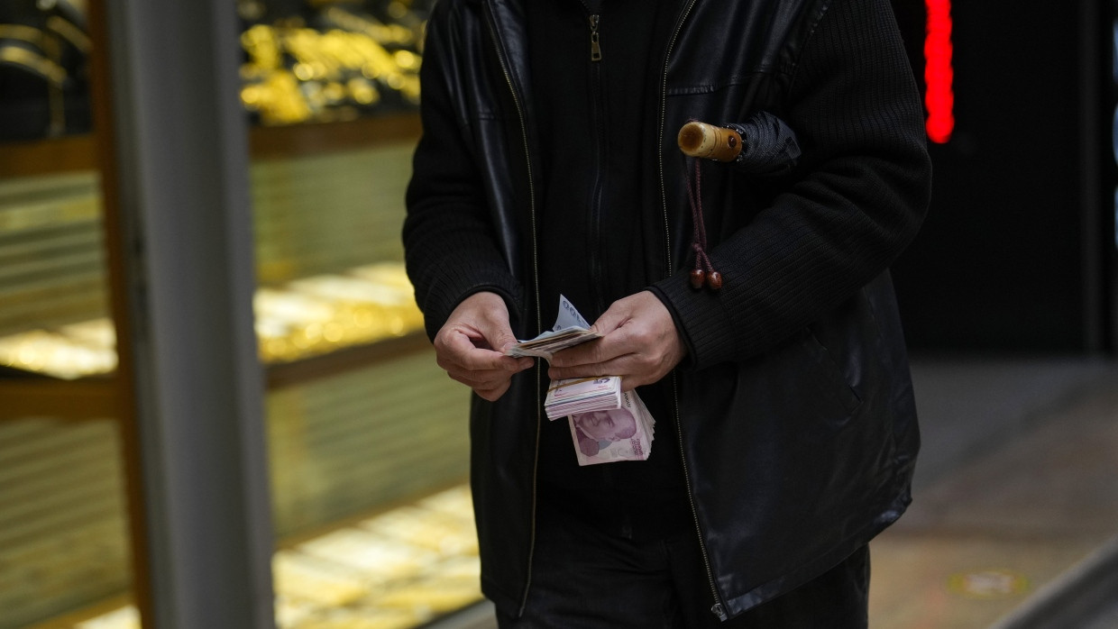 Ein Mann hält türkische Lira-Banknoten vor einem Geldwechselgeschäft im Geschäftsviertel Eminonu.