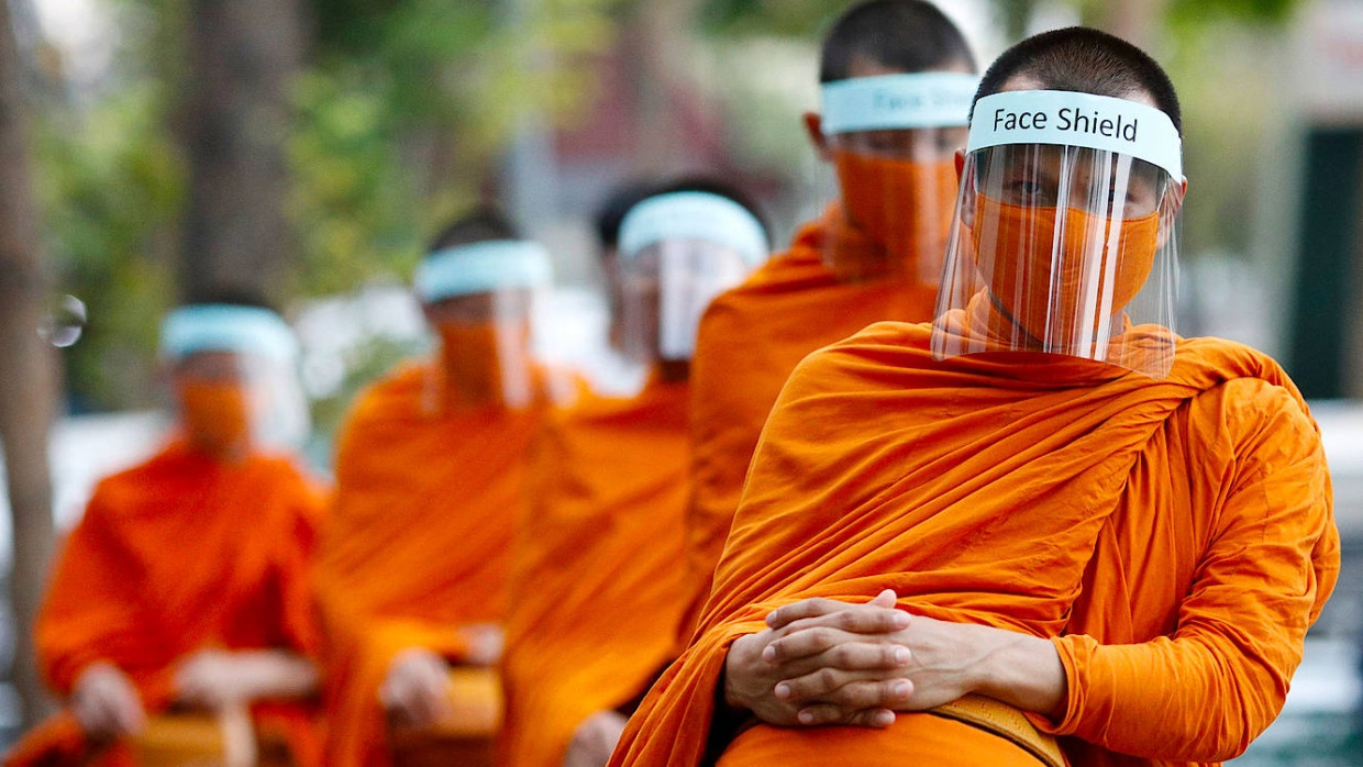 Buddhistische Mönche beten am Dienstag in Bangkok. Die Plastikvisiere sollen die Ausbreitung des Coronavirus verhindern.