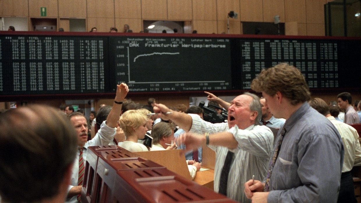 Händler stehen in den späten 1980er Jahren im Börsensaal vor dem computergesteuerten Kursanzeigesystem in der Frankfurter Wertpapierbörse.