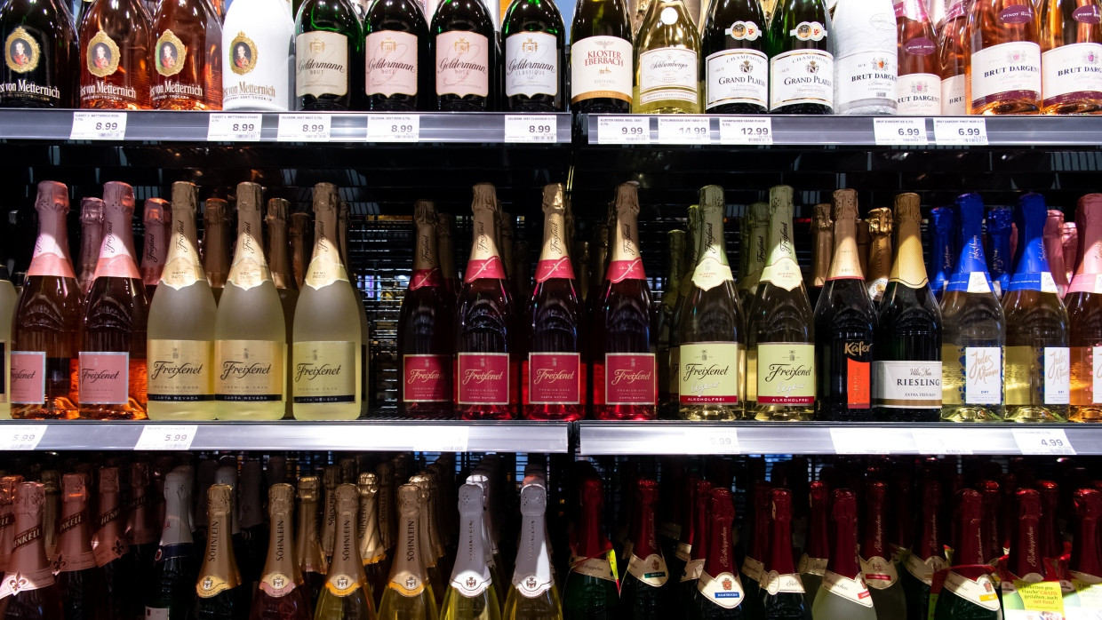 Sektflaschen von verschiedenen Herstellern stehen in einem Supermarktregal.