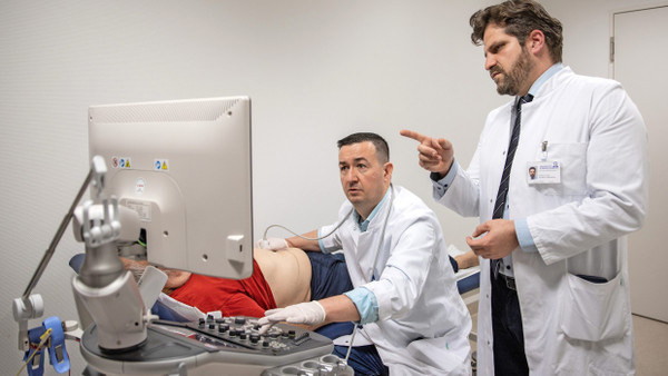 Operation gelungen: Kyriakos Oikonomou (rechts) und Wojciech Derwich untersuchen einen Patienten nach dem Eingriff per Ultraschall.