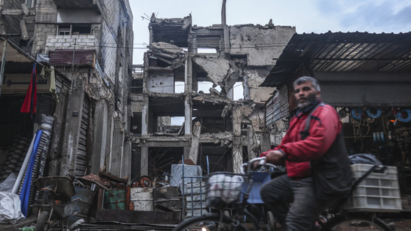 Ein Mann radelt an einem Gebäude am Stadtrand von Damaskus vorbei, das durch Luftangriffe während der Assad-Herrschaft beschädigt wurde (Aufnahme vom 29. Dezember 2024).