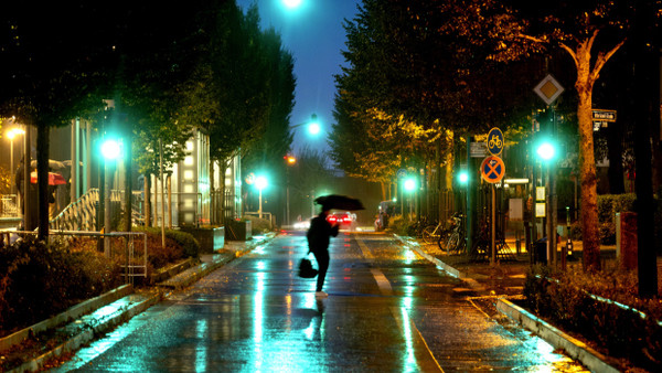 Ein Mann läuft am Donnerstagabend im strömenden Regen über die Riedbergallee in Frankfurt.