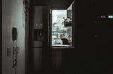 An open fridge in a dark kitchen