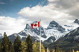 A Canadian flag with the Rocky Mountains in the background