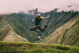 Woman leaping in front of mountains