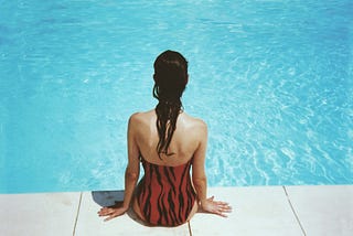 A woman at the edge of a pool, her back to the camera