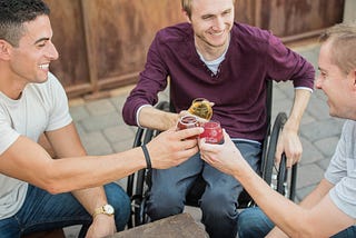 Three men holding drinks smile and toast