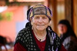 An Eastern European older woman with a head scarf smiles