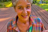 Author standing on her deck holding up a Bombers coaster and graduation photo on a lanyard