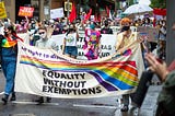 People marching with banners and signs for LGBTQ Equality