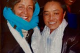 A nun standing with the author outside a rural monastery in Tibet. Both heavily clothed due to high altitude cold.