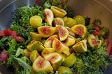 A bowl of salad topped with sliced figs