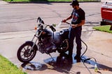 A photo from June 14, 1993, of the author cleaning his motorcycle in a driveway 1000 miles from home.