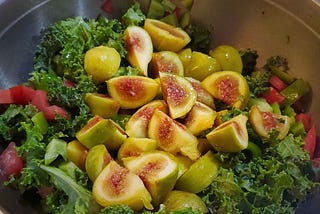 A bowl of salad topped with sliced figs