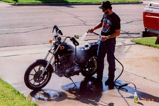 A photo from June 14, 1993, of the author cleaning his motorcycle in a driveway 1000 miles from home.