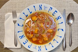 A bowl of vegetable soup, at a place setting.