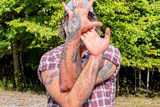 The author in Eagle Arms showing his Native American-style eagle on his right arm, bald eagle on his left arm, and phoenix with flame-piece on his right hand, which is covering his face.