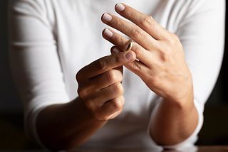 Woman in white shirt taking her wedding ring off