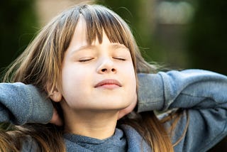 Young natural looking girl with eyes closes, feeling the sun on her pale skin hands behind her head, dreaming.