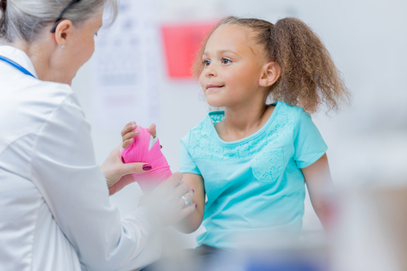 A healthcare provider examining a child’s wrist cast.