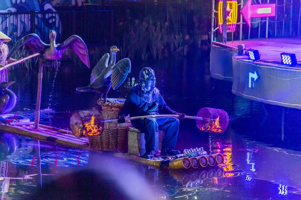 A performer holds a rod with fire pots of burning charcoal attached on either end at an amusement park in Shapingba District, southwest China's Chongqing Municipality on July 21, 2024. /CFP