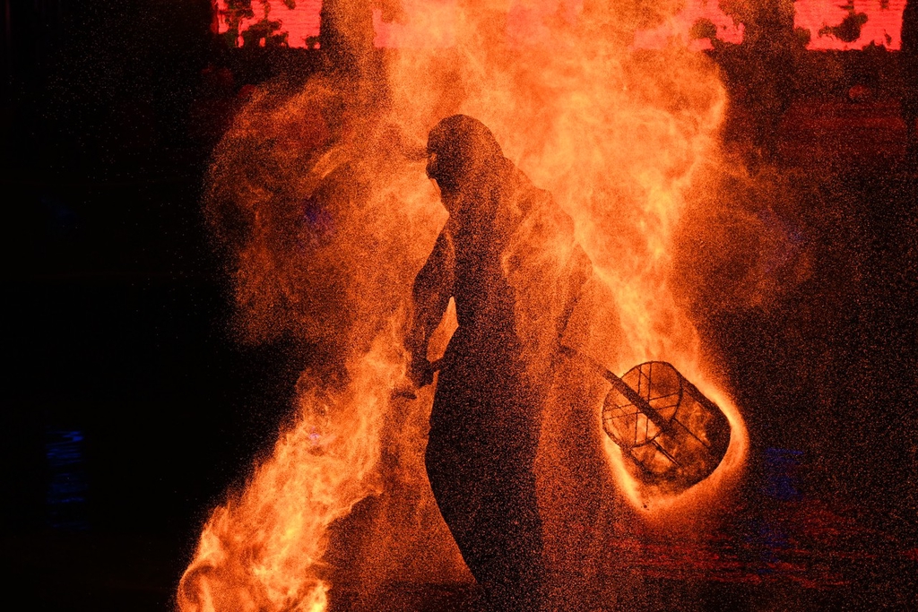 A performer shakes fire pots on a rod to release flames at an amusement park in Shapingba District, southwest China's Chongqing Municipality on July 21, 2024. /CFP