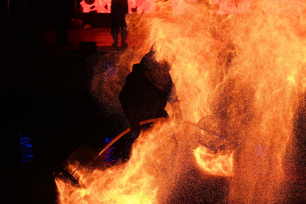 A performer shakes fire pots on a rod to release flames at an amusement park in Shapingba District, southwest China's Chongqing Municipality on July 21, 2024. /CFP