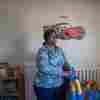 Lakethia Clark stands between a bookcase full of children's books and a toddler bed.