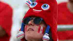 A Canada fan dons an Olympic mascot Phryge hat before the women's quarter-final football match between Canada and Germany during the Paris Olympics.