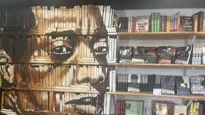 On the left side of this photo, James Baldwin's face is painted on a decorative bookcase inside the Baldwin & Co. bookstore in New Orleans. On the right are books arranged on rows of bookshelves.