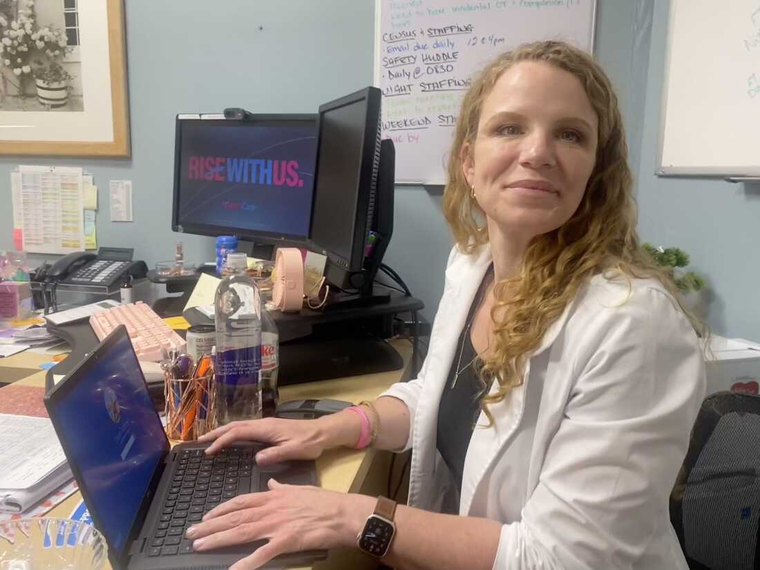 AtlantiCare nurse manager Kathryn Dixon sits with her laptop at a desk.