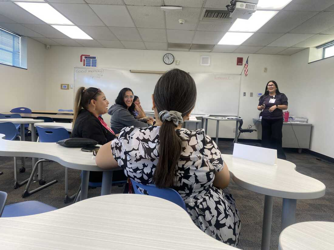 A half dozen women sit in a classroom discussing caregiving topics.