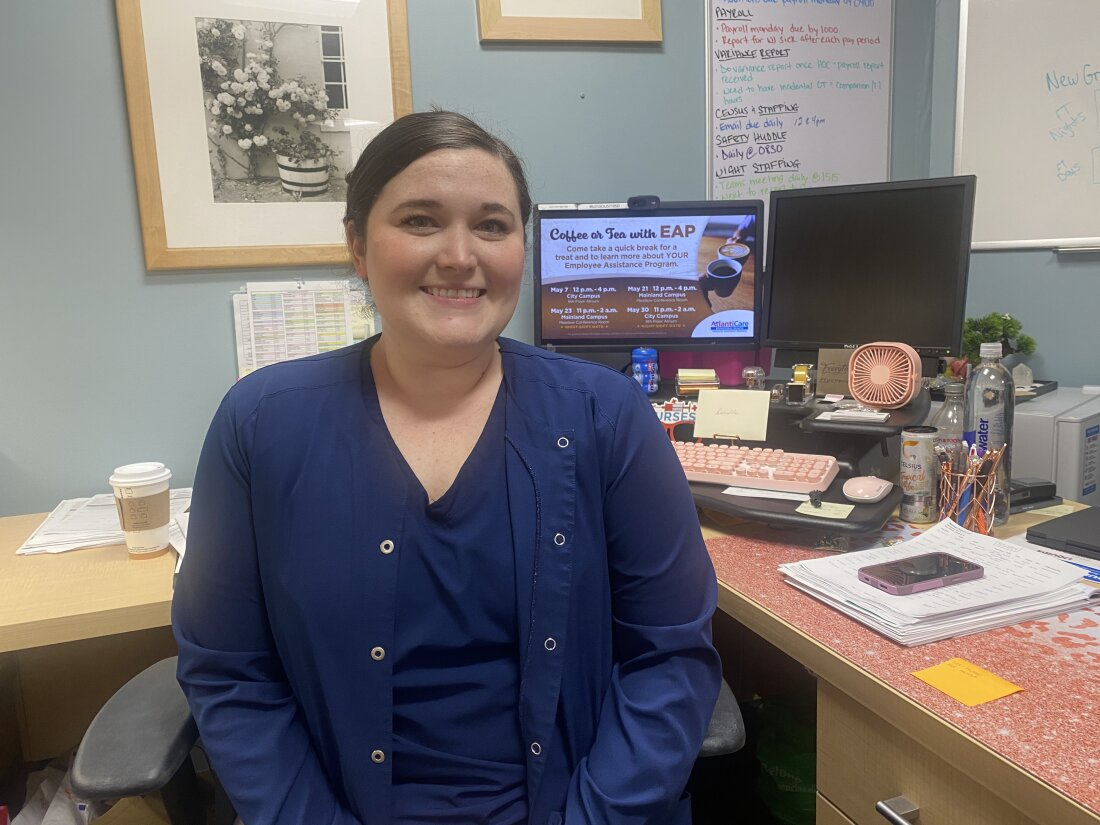 Nurse manager Danielle DiLella sits in her office, with a long to-do list on her white board behind her.