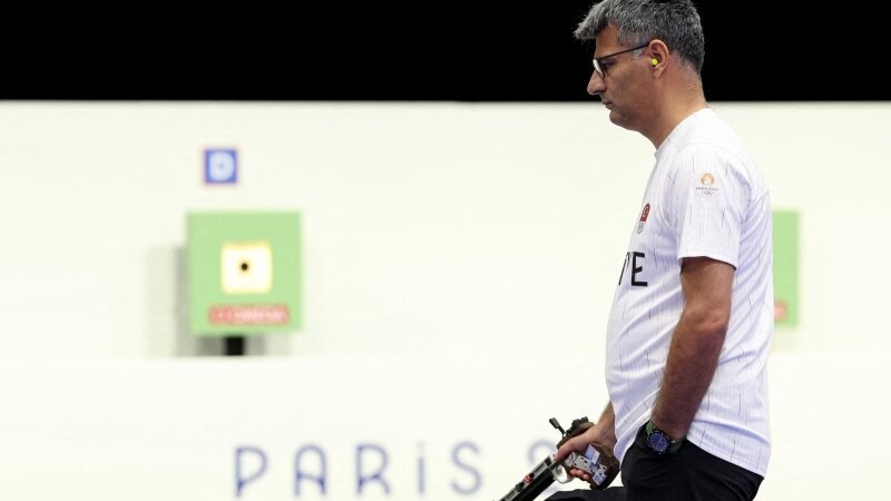 Turkey's Yusuf Dikec, wearing small yellow earplugs, eyeglasses and a white jersey, competes in the shooting 10m air pistol mixed team gold medal match at Chateauroux Shooting Center.