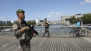 Soldiers patrol on a footbridge over the Seine river, Wednesday, July 17, 2024 in Paris. France's armed forces held a demonstration of the security measures planned on the River Seine, both in and out of the water, to make it safe for athletes and spectators during the opening ceremony of the Paris Olympics. Organizers have planned a parade of about 10,000 athletes through the heart of the French capital on boats on the Seine along a 6-kilometer (3.7-mile) route at sunset on July 26. (AP Photo/Aurelien Morissard)