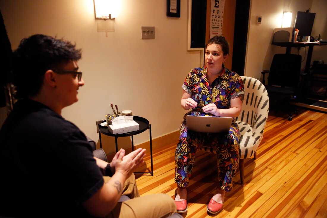 Dr. Arnold sits across from a patient interested in gender-affirming care in her offices in Richmond, Va. The doctor has a laptop computer on her lap. 