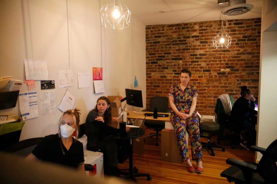 Dr. Stephanie Arnold, a primary care physician, meets with her staff at Seven Hill Family Medicine in Richmond, Va. to discuss the schedule for the day. The room has warm lighting and brick walls.