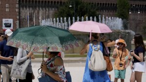 Tourists shelter from the sun in front of the Sforzesco Castle in Milan, Italy, on Tuesday. Weather alerts, forest fires, melting pavement in cities: A sizzling heat wave has sent temperatures in parts of central and southern Europe soaring toward 104 degrees Fahrenheit (40 degrees Celsius) in some places.