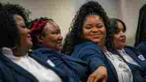 This photo shows multiple Black women seated at the graduation ceremony for Morehouse School of Medicine's first class of rural doulas. The women are all wearing dark blue blazers, and in the center is Bristeria Clark, with a big smile on her face.